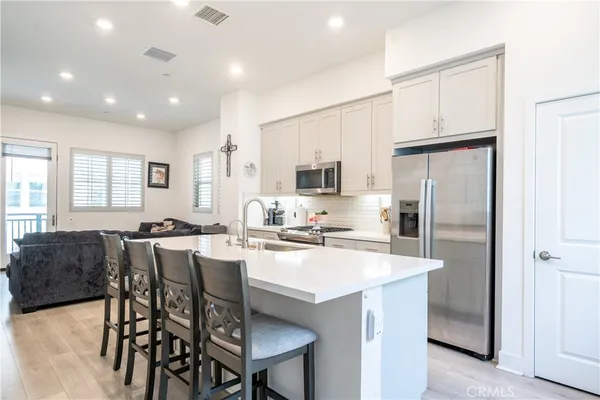 a kitchen with stainless steel appliances a table chairs refrigerator and microwave