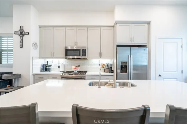 a kitchen with stainless steel appliances kitchen island granite countertop a stove a sink a refrigerator and white cabinets