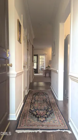 a view of a hallway with wooden floor and a refrigerator