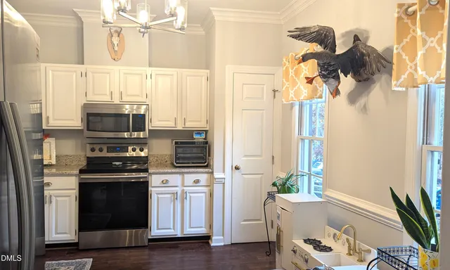 a kitchen with stainless steel appliances a stove a microwave and a potted plant