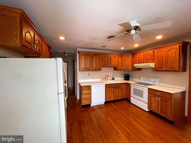 a kitchen with a wooden floor stove top oven and refrigerator
