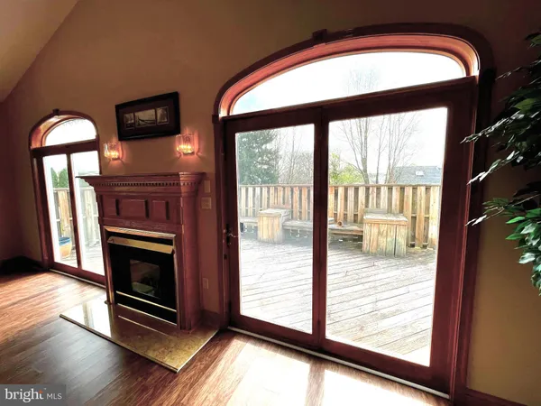 a view of an empty room with wooden floor fire place and a window