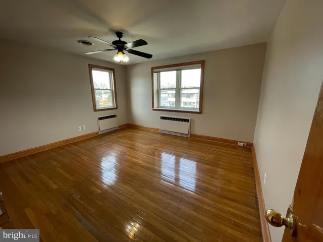 a view of an empty room with window and wooden floor