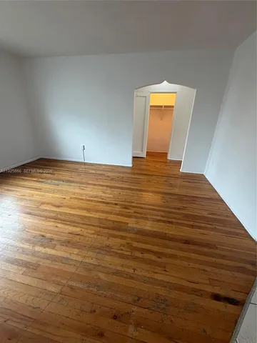 a view of empty room with window and wooden floor
