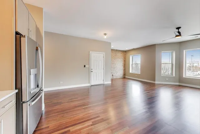 a view of a kitchen with a refrigerator and wooden floor