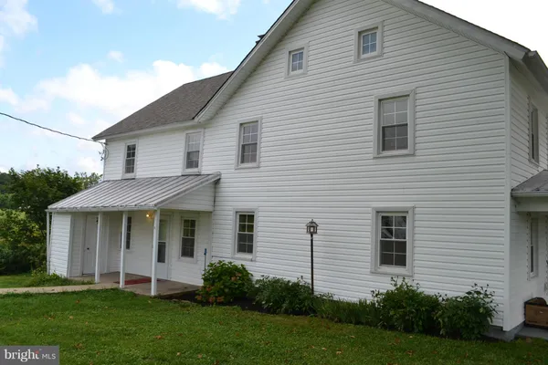 a view of a white house next to a yard