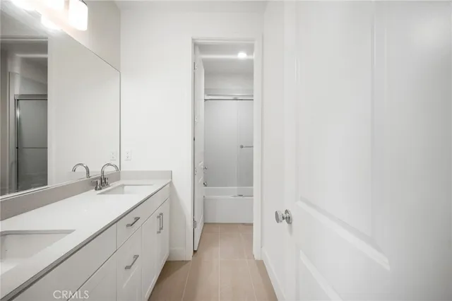 a bathroom with a double vanity sink a toilet and shower