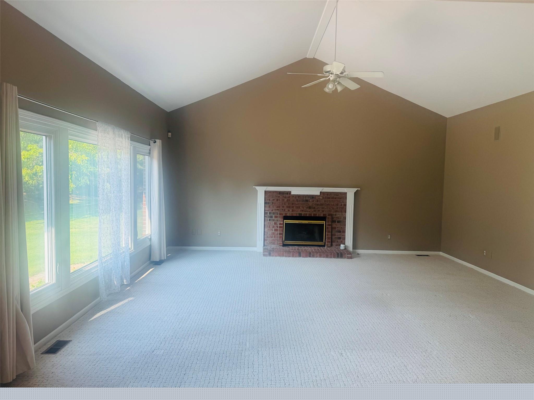 171 Millstone Road Troy, MI 48084 - Photo 8 of 43 Spacious room featuring vaulted ceilings, a brick fireplace with a white mantel, and a ceiling fan