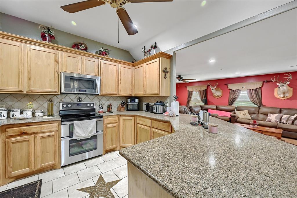 3138 Scarbrough Road Sadler, TX 76264 - Photo 18 of 40 a kitchen with stainless steel appliances granite countertop a sink stove and cabinets
