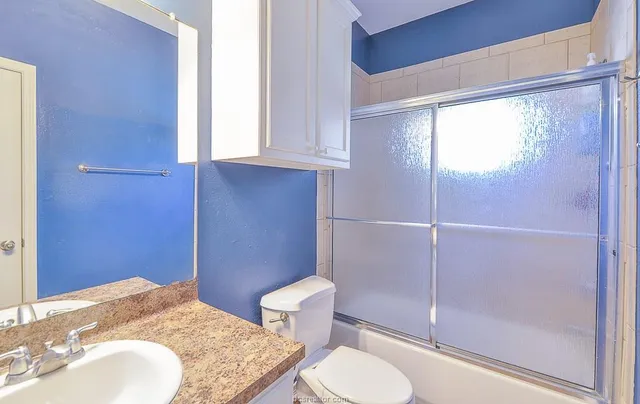 a bathroom with a granite countertop sink toilet and shower