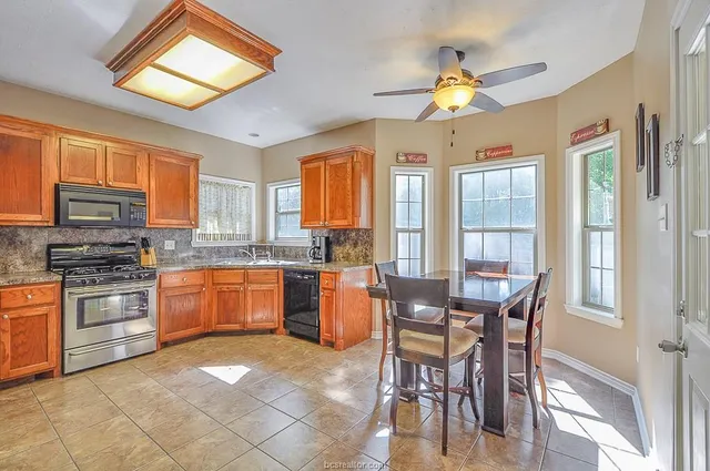 a kitchen with stainless steel appliances granite countertop a stove a sink dishwasher a dining table and chairs with wooden floor