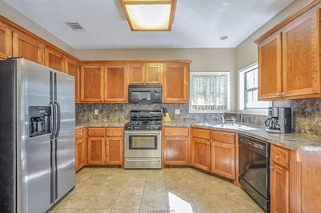 a kitchen with stainless steel appliances granite countertop a refrigerator stove top oven and sink