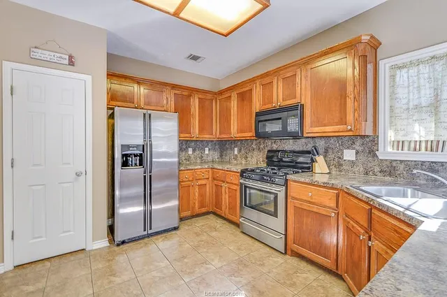 a kitchen with stainless steel appliances granite countertop a refrigerator and a sink