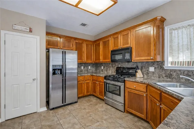 a kitchen with stainless steel appliances granite countertop a refrigerator stove and sink