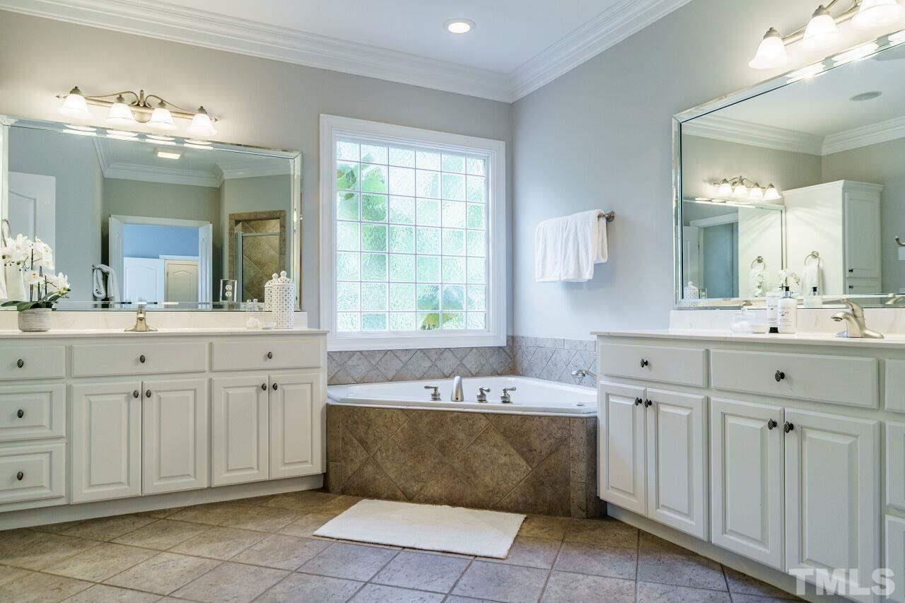 4813 Patton Ridge Court Raleigh, NC 27612 - Photo 16 of 30 a bathroom with a sink mirror and a bathtub