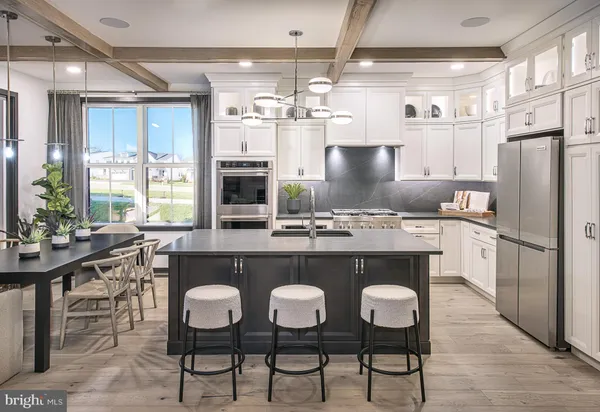 a kitchen with stainless steel appliances granite countertop a table chairs stove and refrigerator
