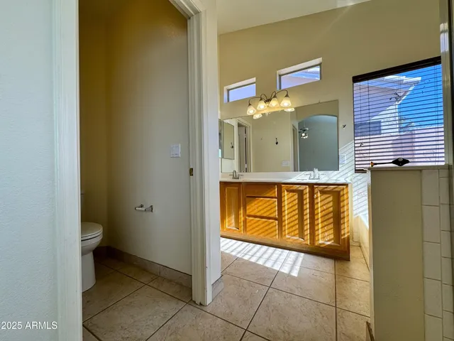 an empty room with a chandelier fan and wooden floor