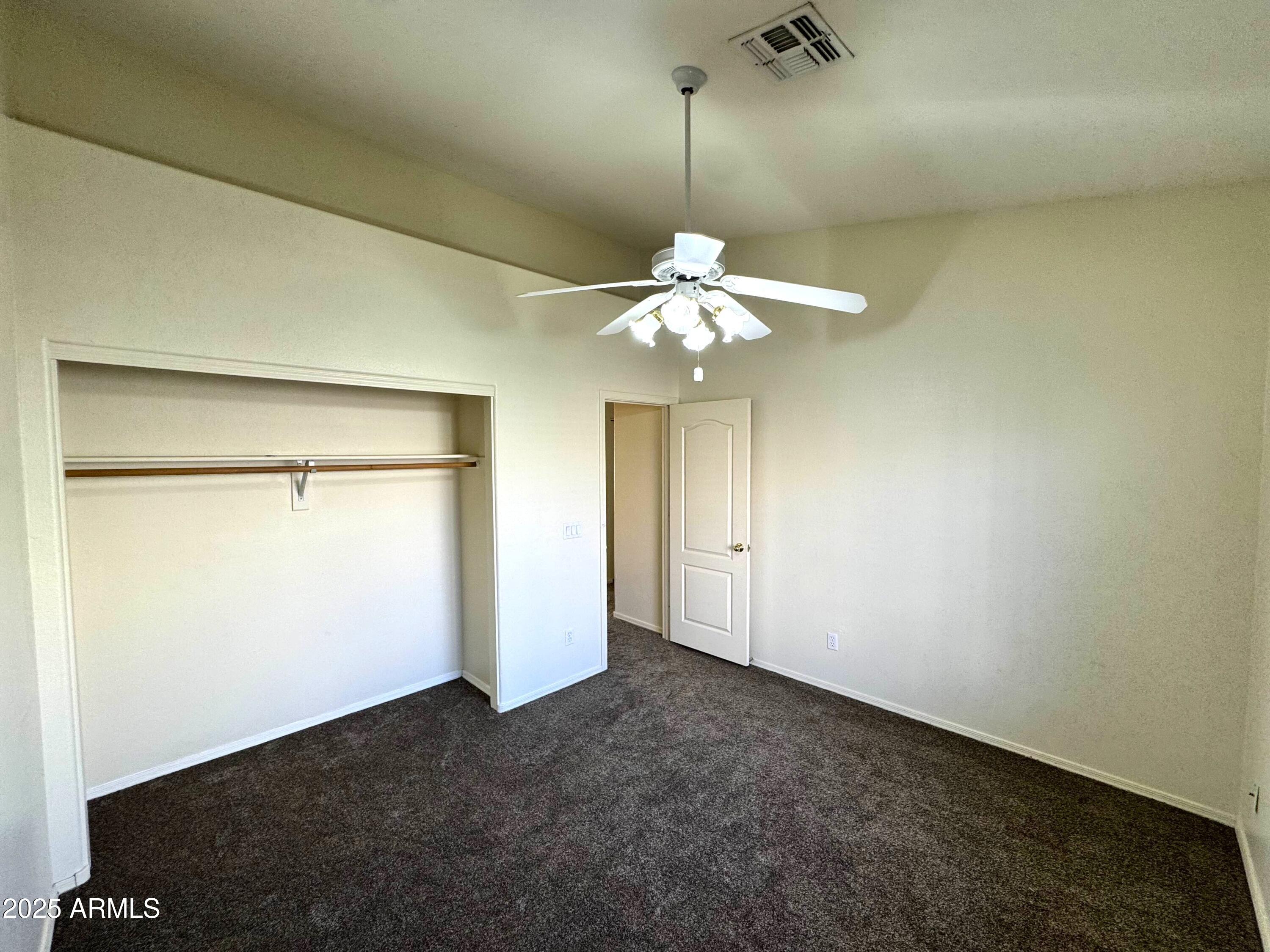 4906 East Brown Road, Unit 38 Mesa, AZ 85205 - Photo 9 of 14 an empty room with a chandelier fan and wooden floor