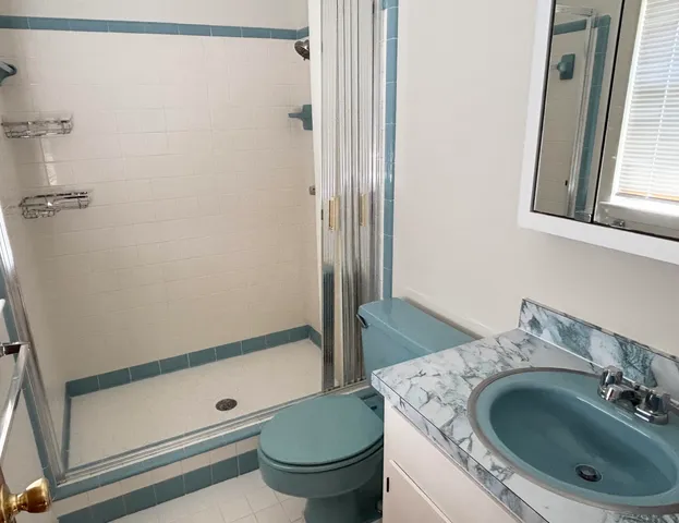 a bathroom with a granite countertop sink toilet and shower