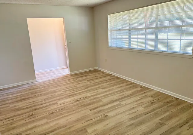 an empty room with wooden floor and windows