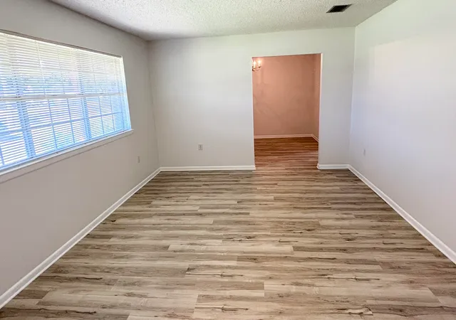 a view of an empty room with wooden floor and a window