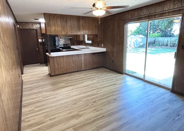 a view of kitchen with stainless steel appliances granite countertop a sink a stove a refrigerator with wooden cabinets and wooden floor