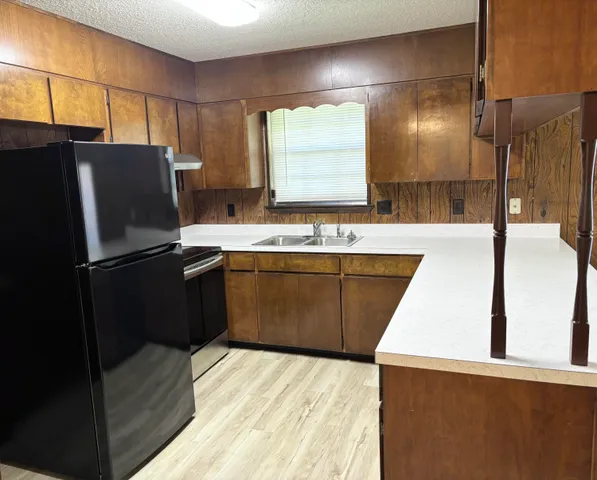 a kitchen with stainless steel appliances a sink a stove a refrigerator a washer dryer and white cabinets