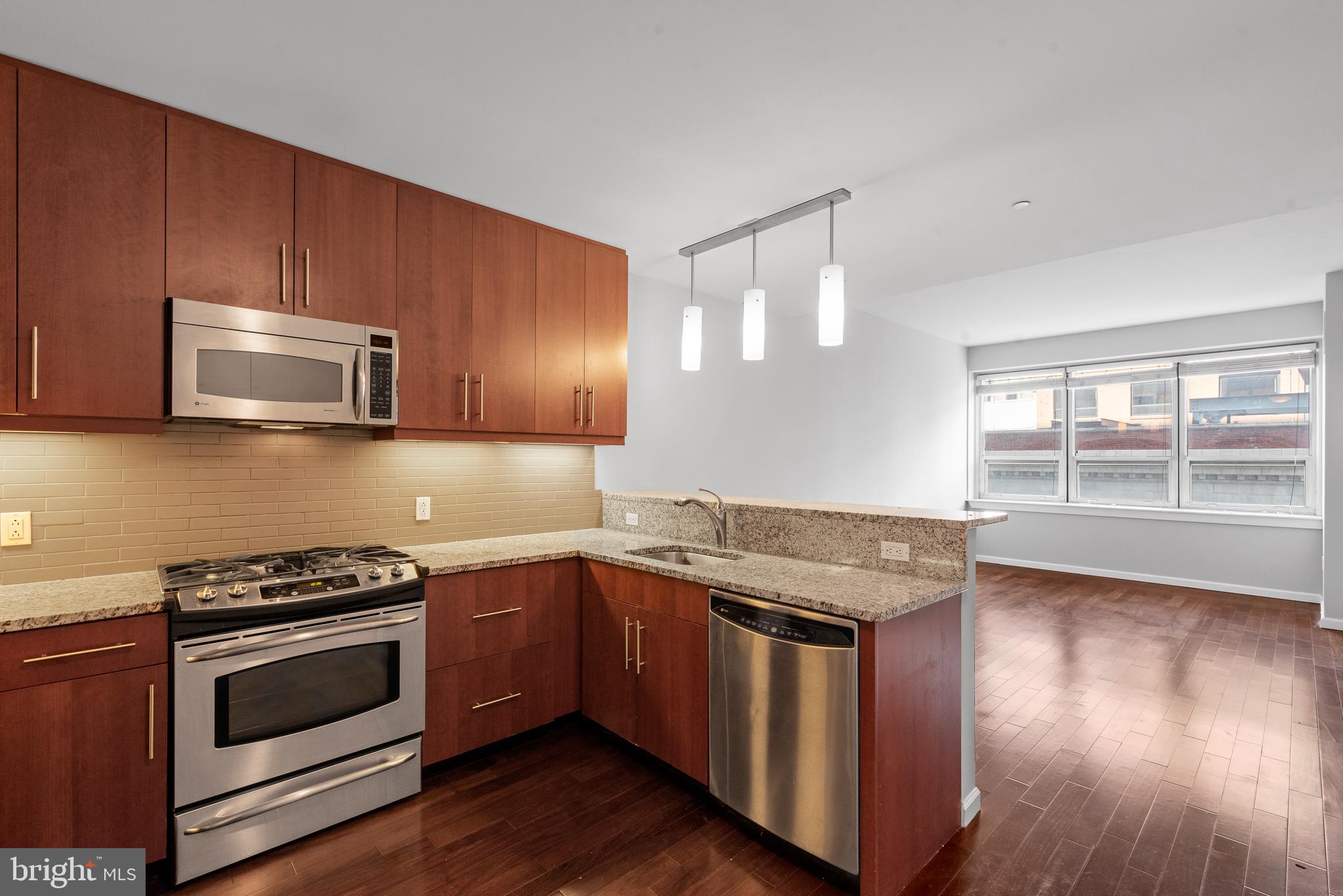1425 Locust Street, Unit 9E Philadelphia, PA 19102 - Photo 8 of 15 a kitchen with stainless steel appliances wooden cabinets and a stove top oven