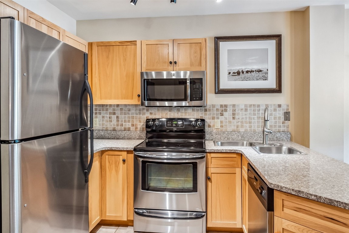 100 Dercum Square, Unit 8386 Keystone, CO 80435 - Photo 14 of 34 a kitchen with stainless steel appliances granite countertop a refrigerator a stove and a sink with wooden floor