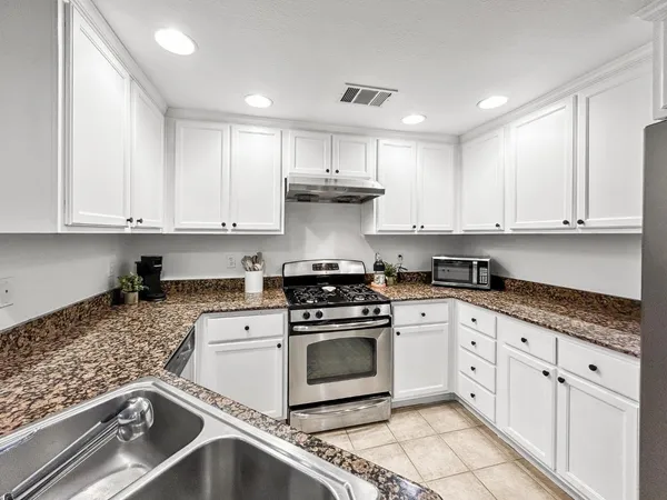 a kitchen with granite countertop stainless steel appliances granite countertop a sink stove and refrigerator