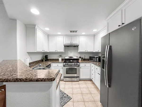 a kitchen with granite countertop white cabinets and stainless steel appliances