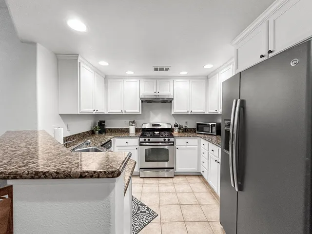 a kitchen with granite countertop white cabinets and stainless steel appliances
