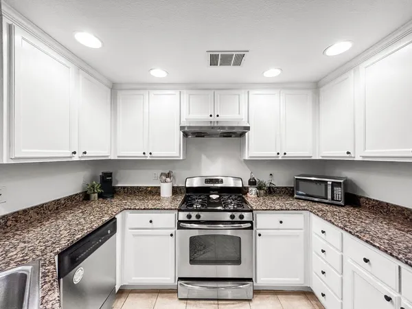 a kitchen with granite countertop a sink a stove and cabinets