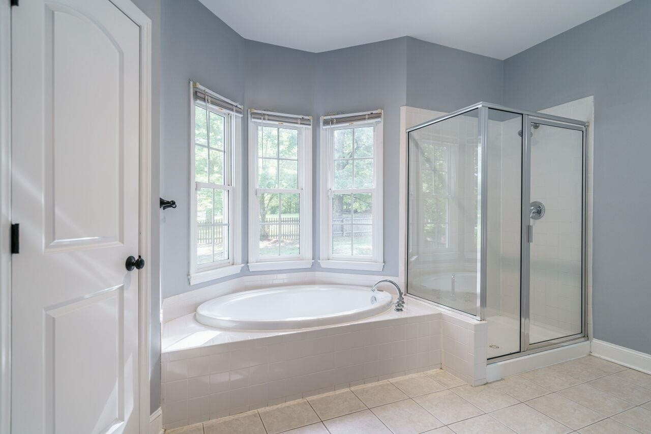4202 Holt School Road Durham, NC 27704 - Photo 19 of 27 Your Oasis Awaits! Indulge in the ultimate relaxation with this luxurious bath featuring a garden tub and a spacious walk-in shower. Master Suite