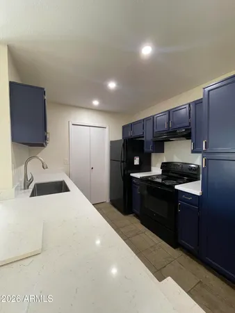 a kitchen with granite countertop a sink cabinets and stainless steel appliances