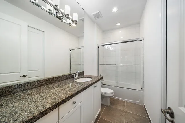 a bathroom with a granite countertop sink a toilet and shower