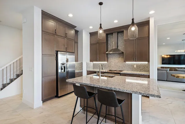 a kitchen with stainless steel appliances granite countertop a kitchen island a stove and a refrigerator