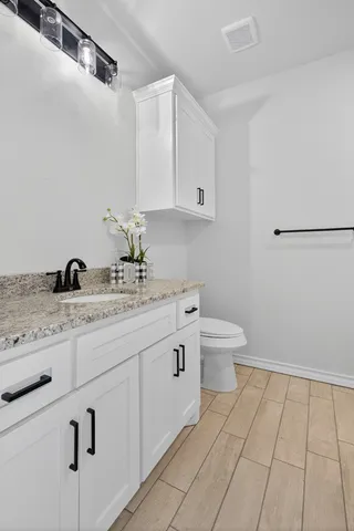 a bathroom with a granite countertop sink a toilet and mirror