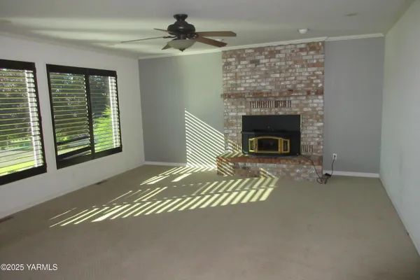a living room with a fireplace furniture a ceiling fan and a window