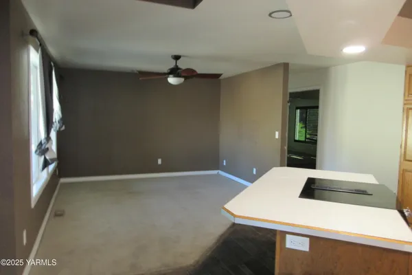 a view of a room with a ceiling fan and carpet