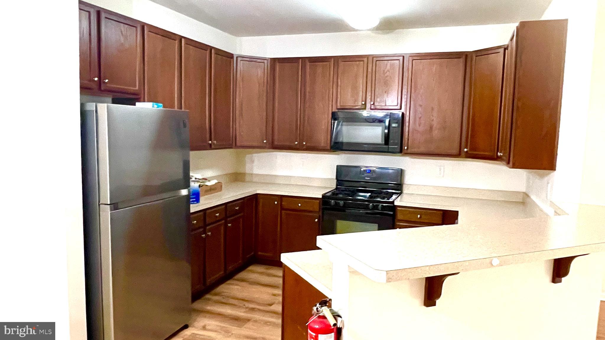 413 Timberlake Drive Ewing, NJ 08618 - Photo 5 of 26 a kitchen with kitchen island granite countertop wooden cabinets a stove a sink and a refrigerator
