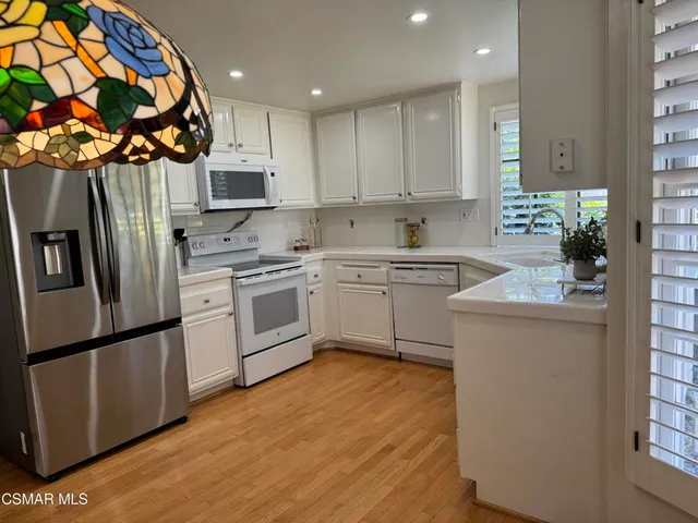 a kitchen with stainless steel appliances a sink a stove a refrigerator and cabinets