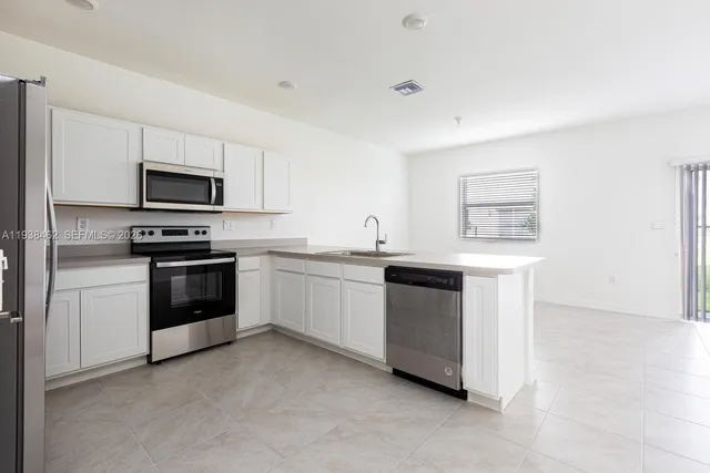 a kitchen with white cabinets and stainless steel appliances