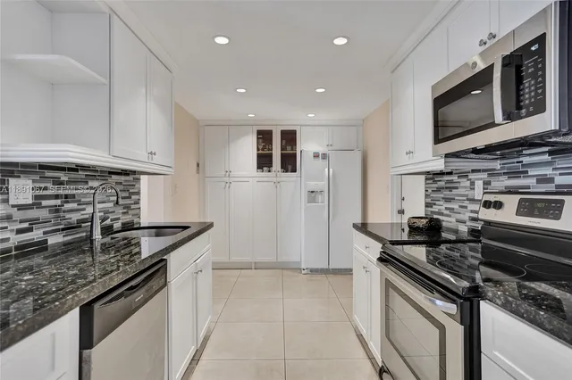 a kitchen with granite countertop a sink and a refrigerator