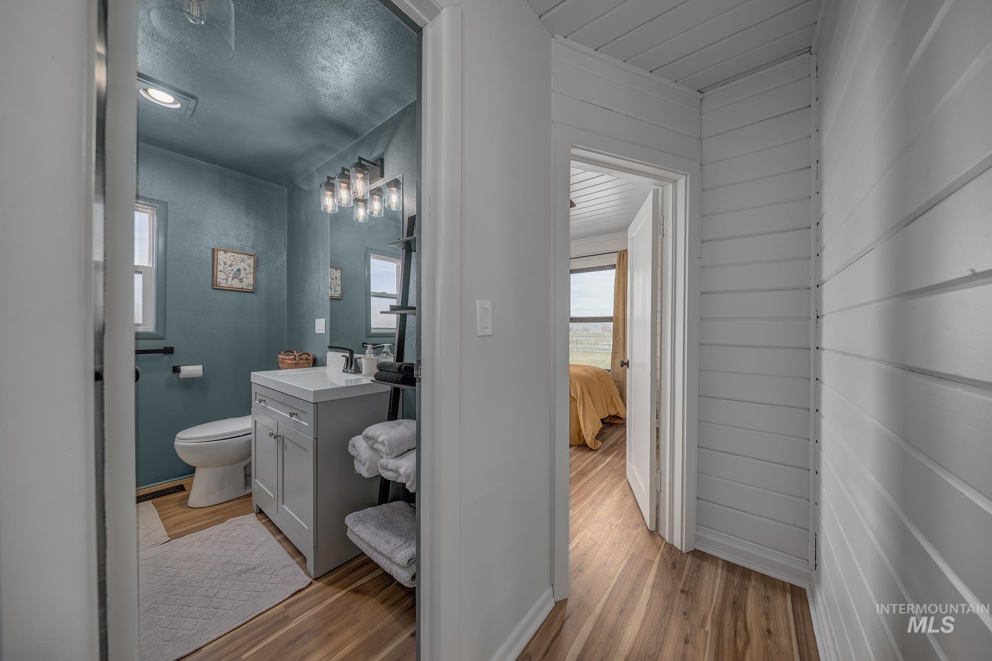 1009 County Road 70 Weiser, ID 83672 - Photo 11 of 48 Ensuite bathroom with vanity, light wood-style floors, and wood walls