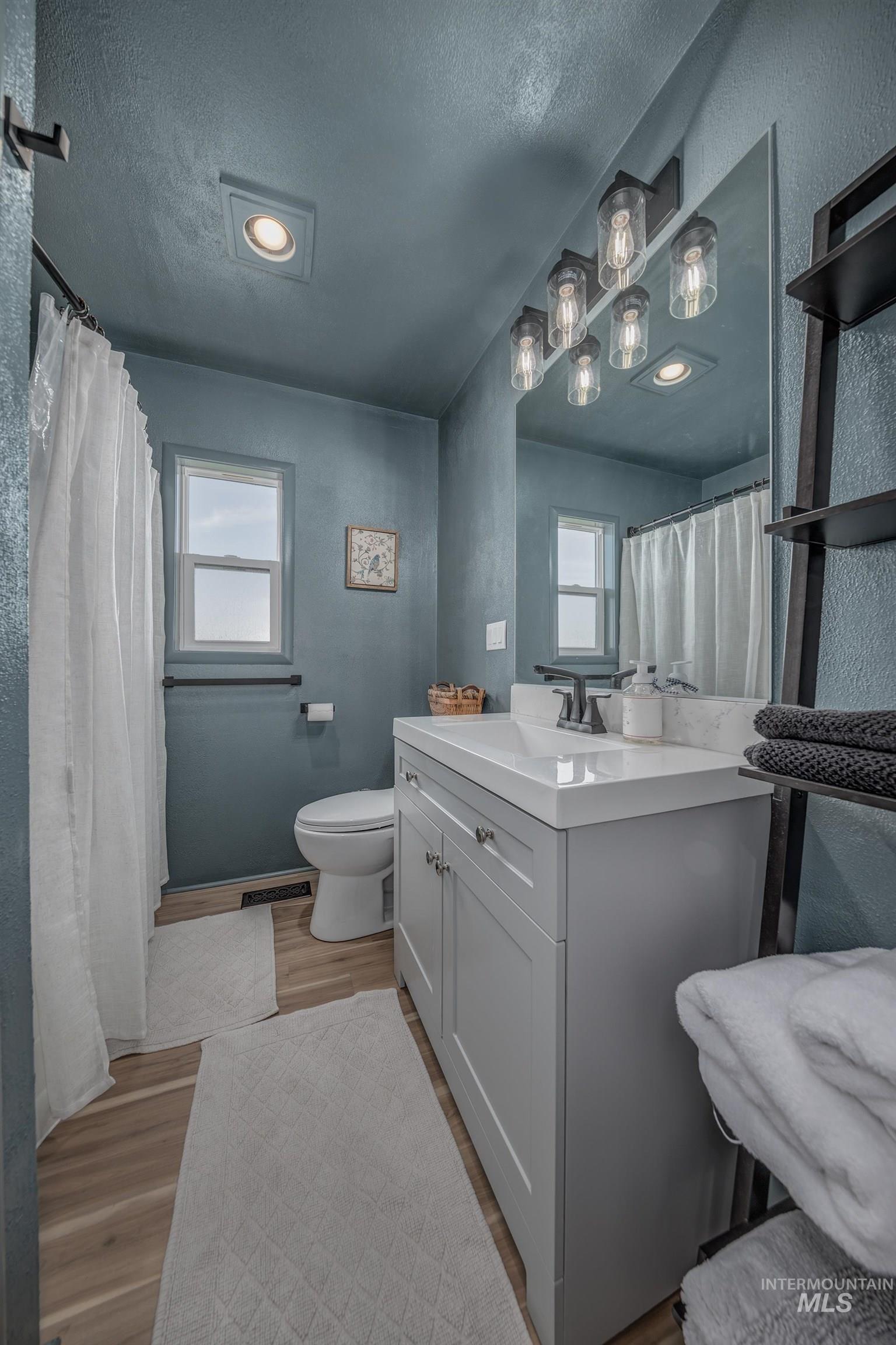 1009 County Road 70 Weiser, ID 83672 - Photo 12 of 48 Full bath with a textured wall, a textured ceiling, vanity, light wood-type flooring, and curtained shower