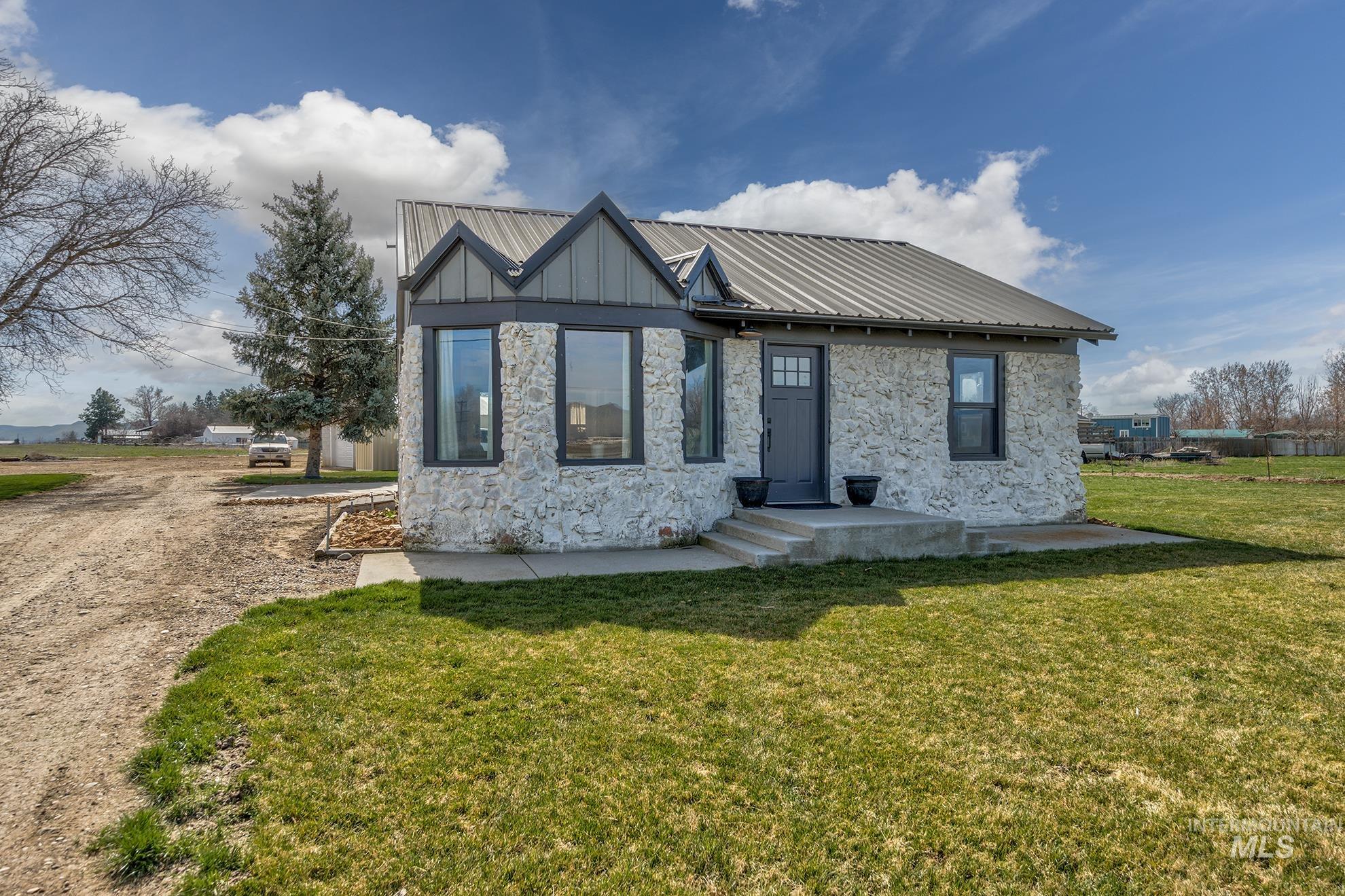 1009 County Road 70 Weiser, ID 83672 - Photo 3 of 48 View of front facade with stone siding, a metal roof, and a front lawn