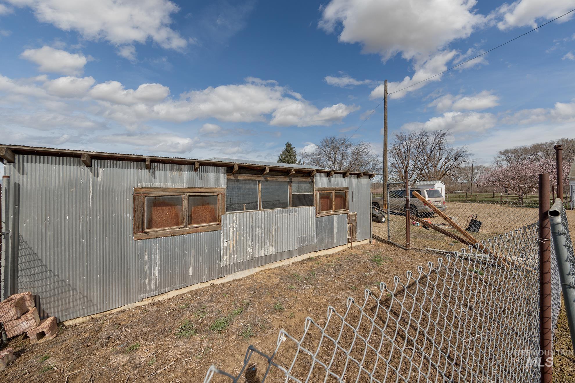 1009 County Road 70 Weiser, ID 83672 - Photo 39 of 48 View of property exterior featuring a sunroom, a metal roof, and a gate