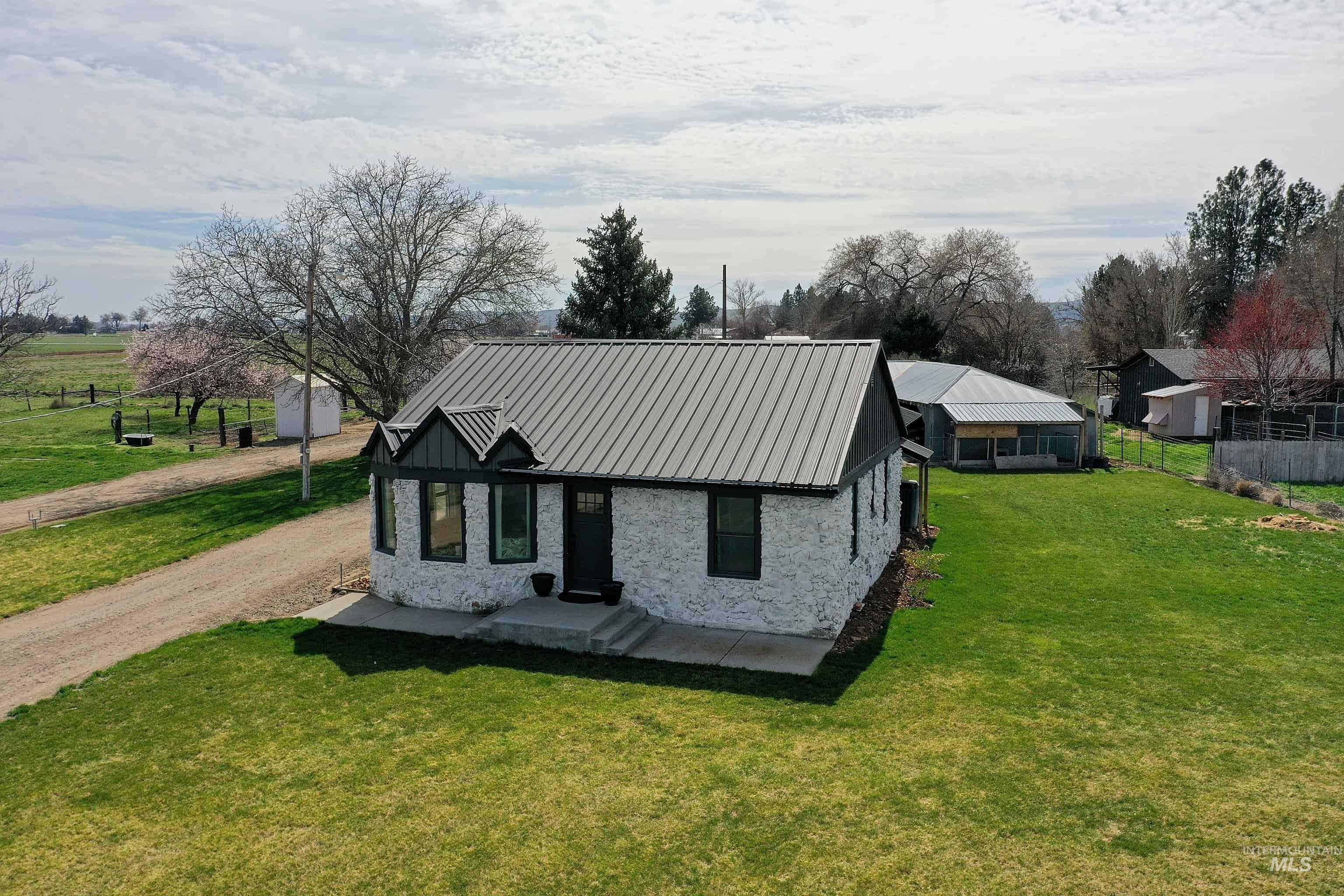 1009 County Road 70 Weiser, ID 83672 - Photo 45 of 48 View of front facade with a metal roof, stone siding, a view of rural / pastoral area, and driveway