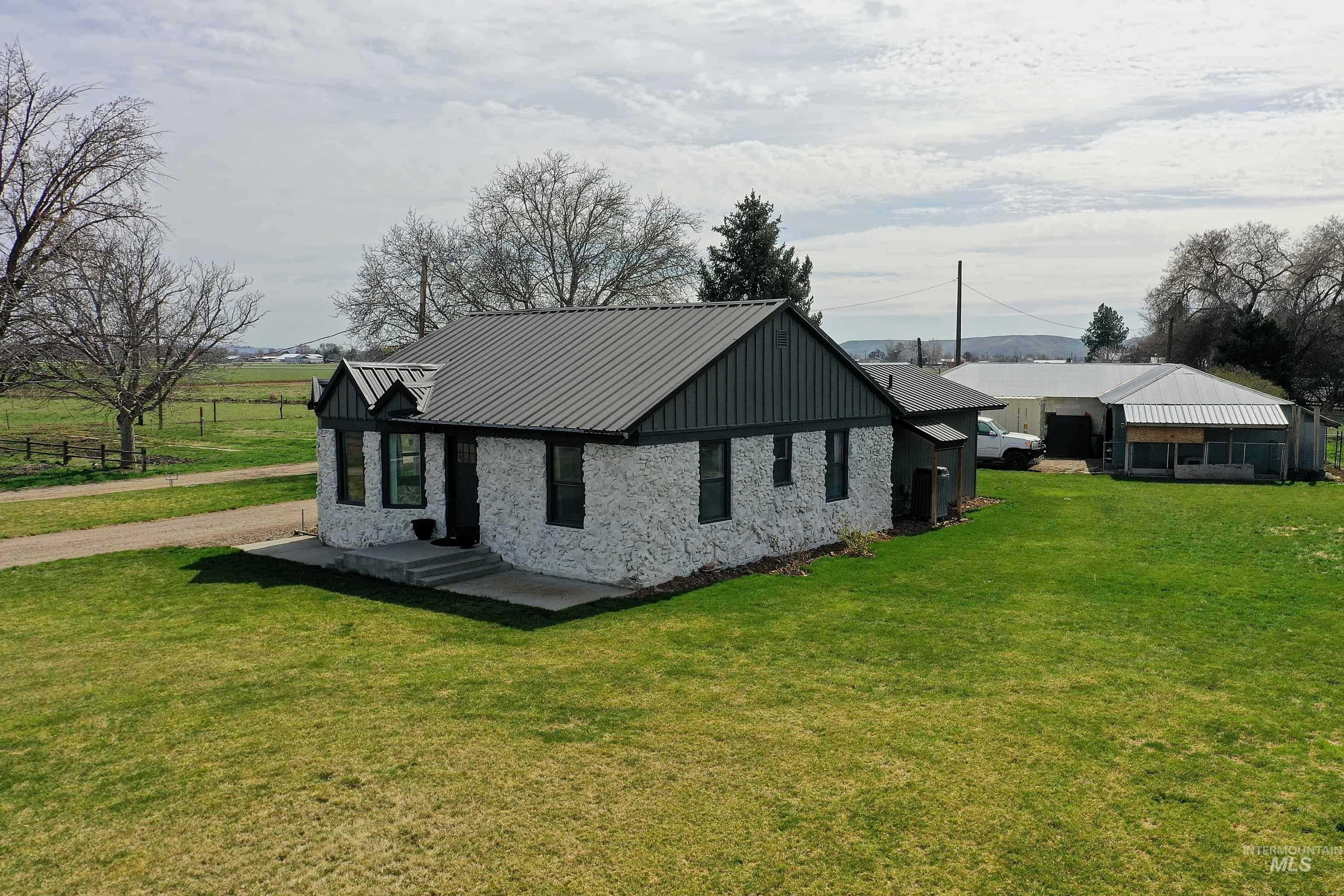 1009 County Road 70 Weiser, ID 83672 - Photo 46 of 48 View of property exterior featuring a metal roof, a lawn, and stone siding